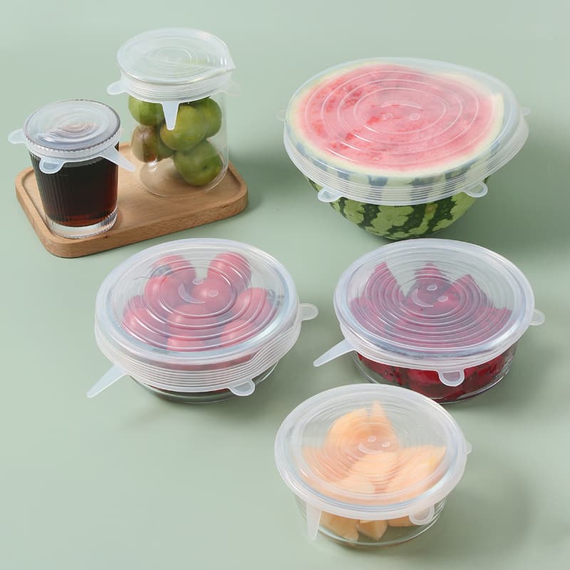 Six clear silicone lids stretched over bowls, jars and half a melon